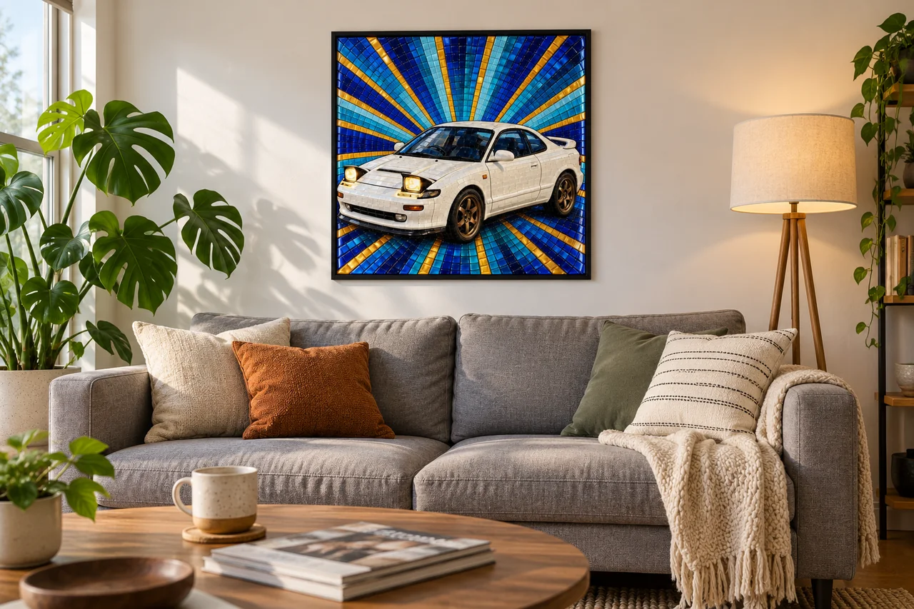A white '90s sports coupe in glossy mosaic tiles on a blue and gold sunburst, in a thin black frame above a grey sofa with cushions and a knitted throw